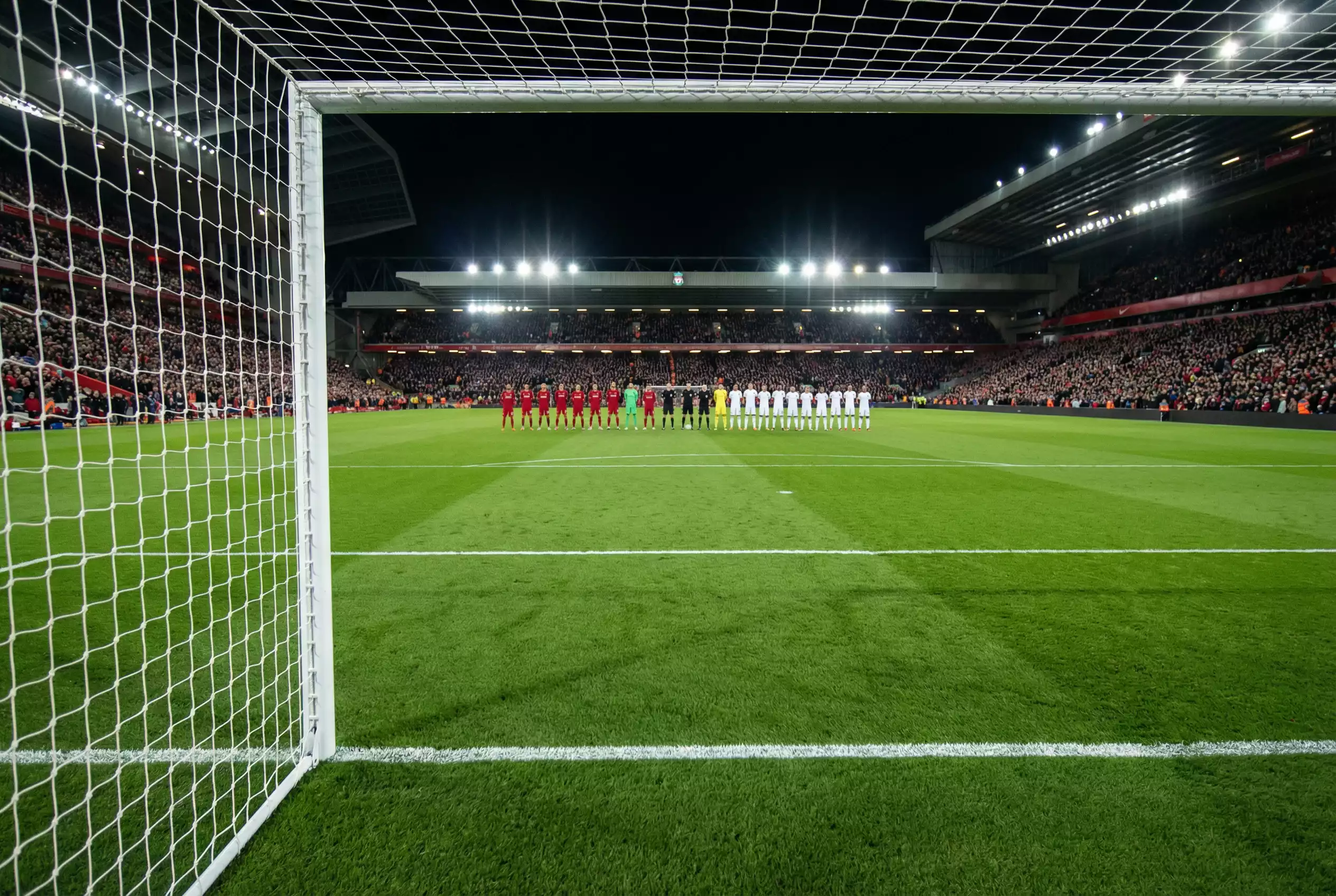 Campo di calcio con linee bianche e due squadre schierate prima del fischio